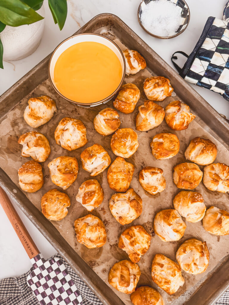 overhead view of pretzel bites on sheet tray with bowl of cheese sauce on it