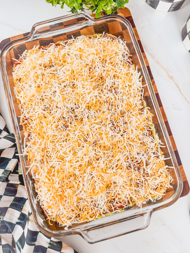 A glass baking dish with layered beans, salsa, and shredded cheese.