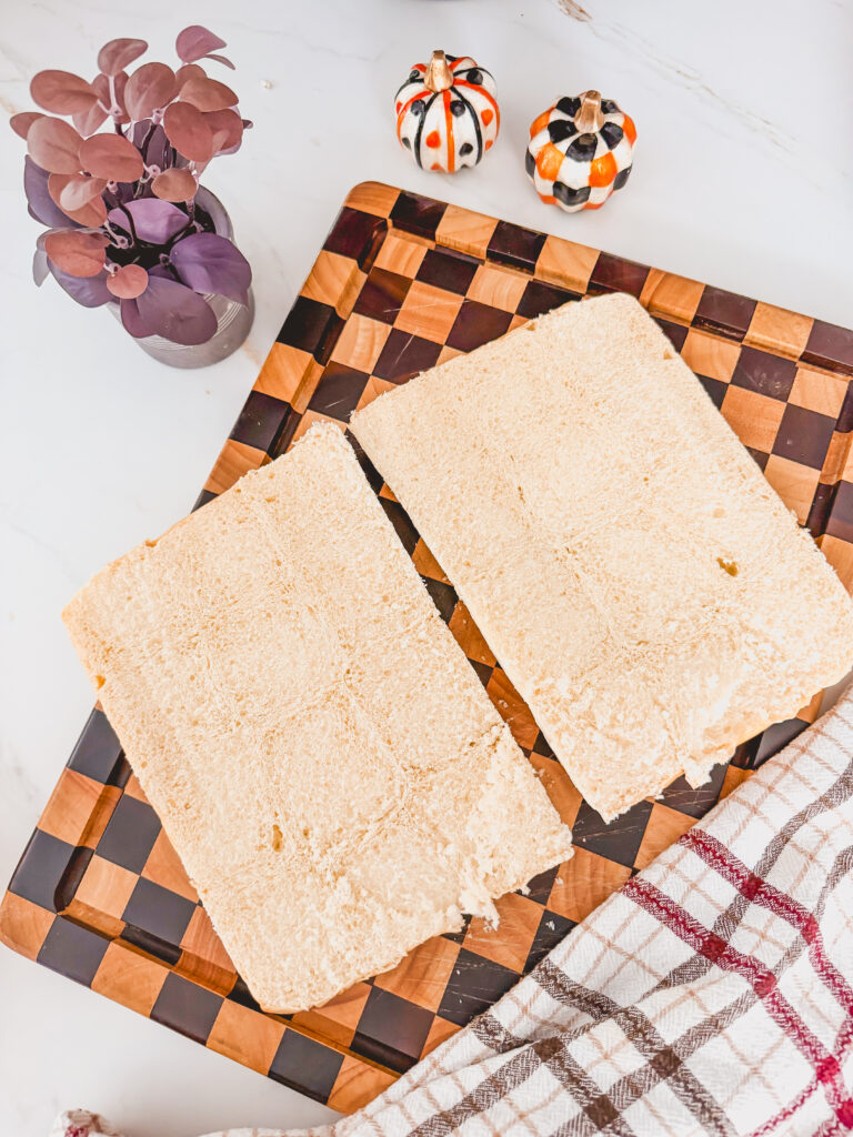 Hawaiian rolls cut open and attached on a checkered cutting board.