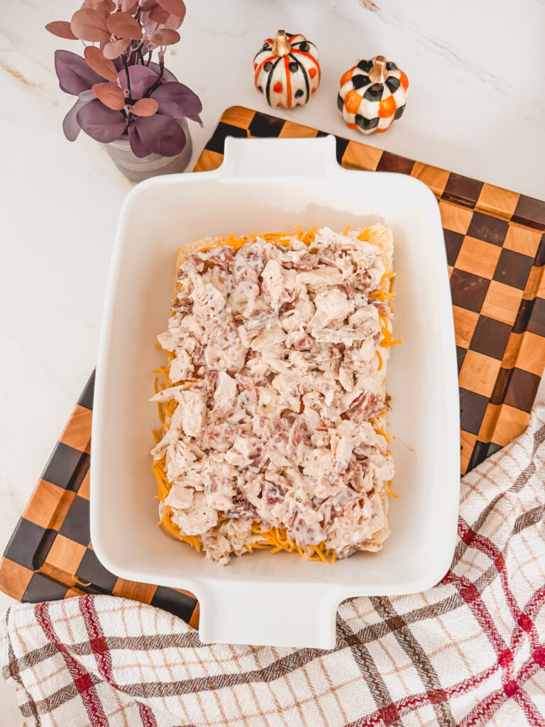A white baking dish with chicken, ranch, and bacon on the bottom half of the buns.