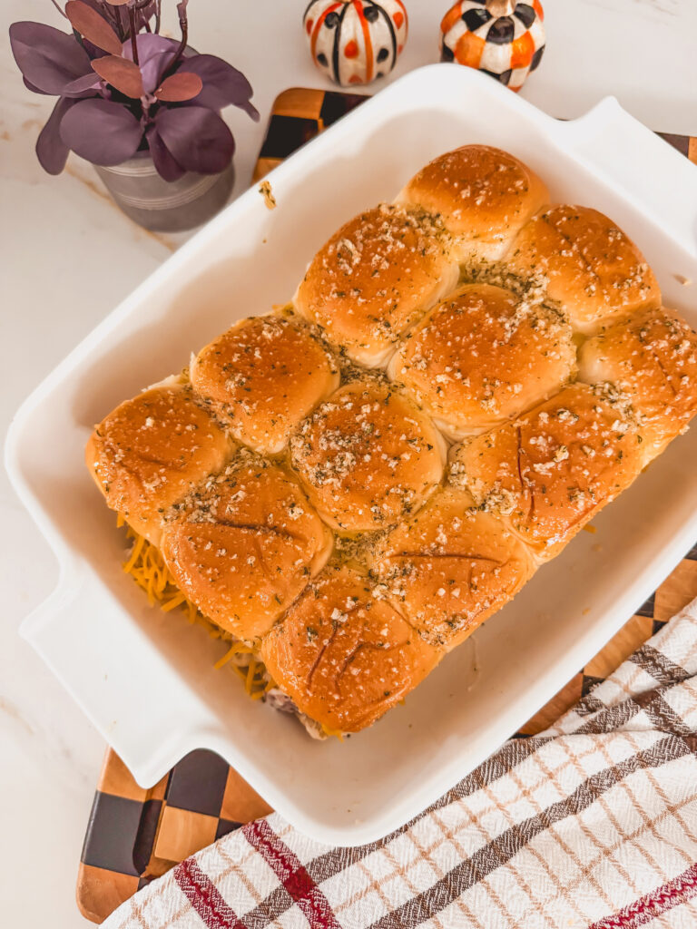 White baking dish with baked chicken bacon sliders.