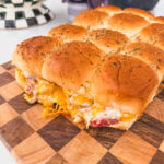Close up of chicken bacon ranch sliders on a checkered cutting board.