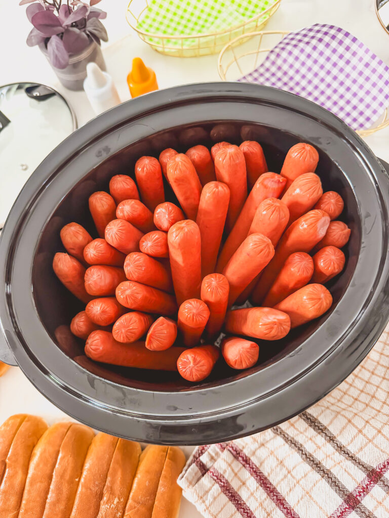A slow cooker with hot dogs in the crock.