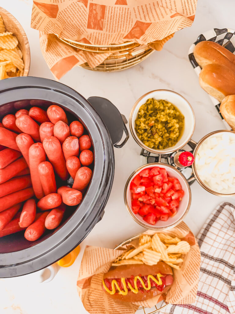 Overhead image of slow cooker hot dogs with toppings.