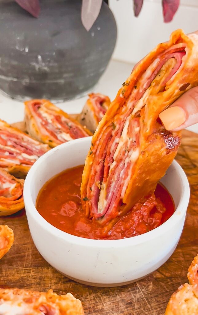 dipping italian stromboli into pizza sauce