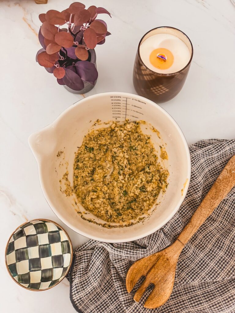 breadcrumb and spice mixture in white mixing bowl with wooden spoon and dish towel next to it.