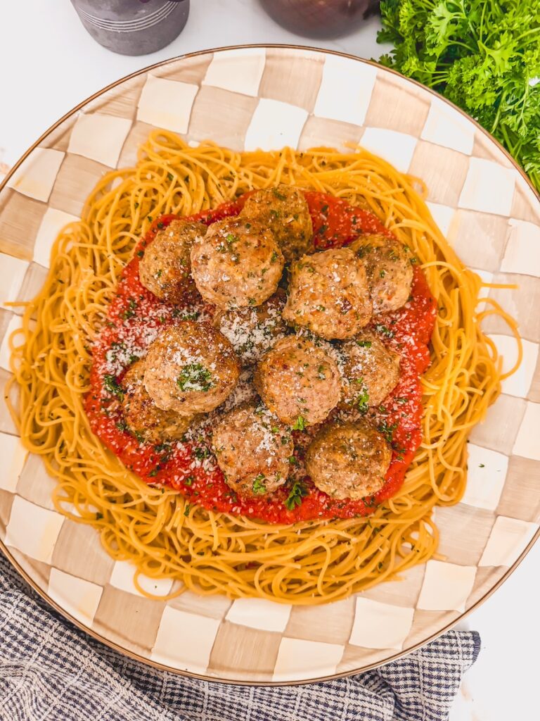 overhead of pasta, sauce and meatballs with fresh herbs in background