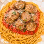 platter of pasta, sauce and meatballs garnished with cheese and herbs