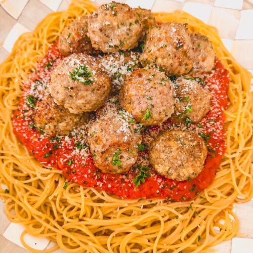 platter of pasta, sauce and meatballs garnished with cheese and herbs