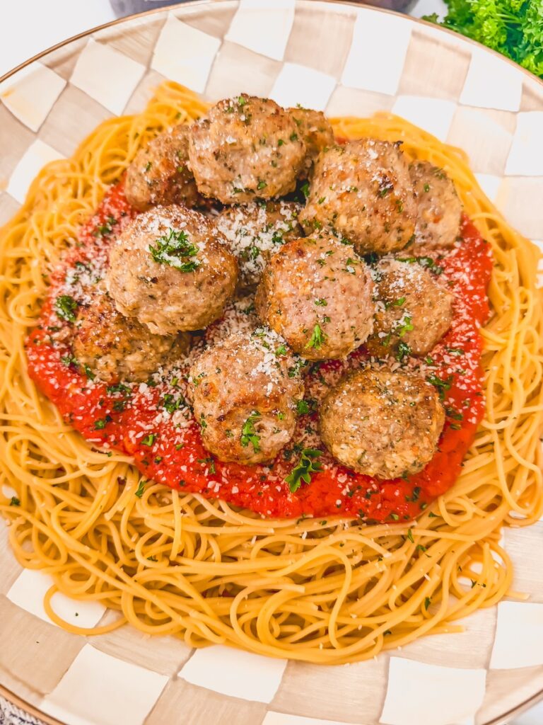 platter of pasta, sauce and meatballs garnished with cheese and herbs
