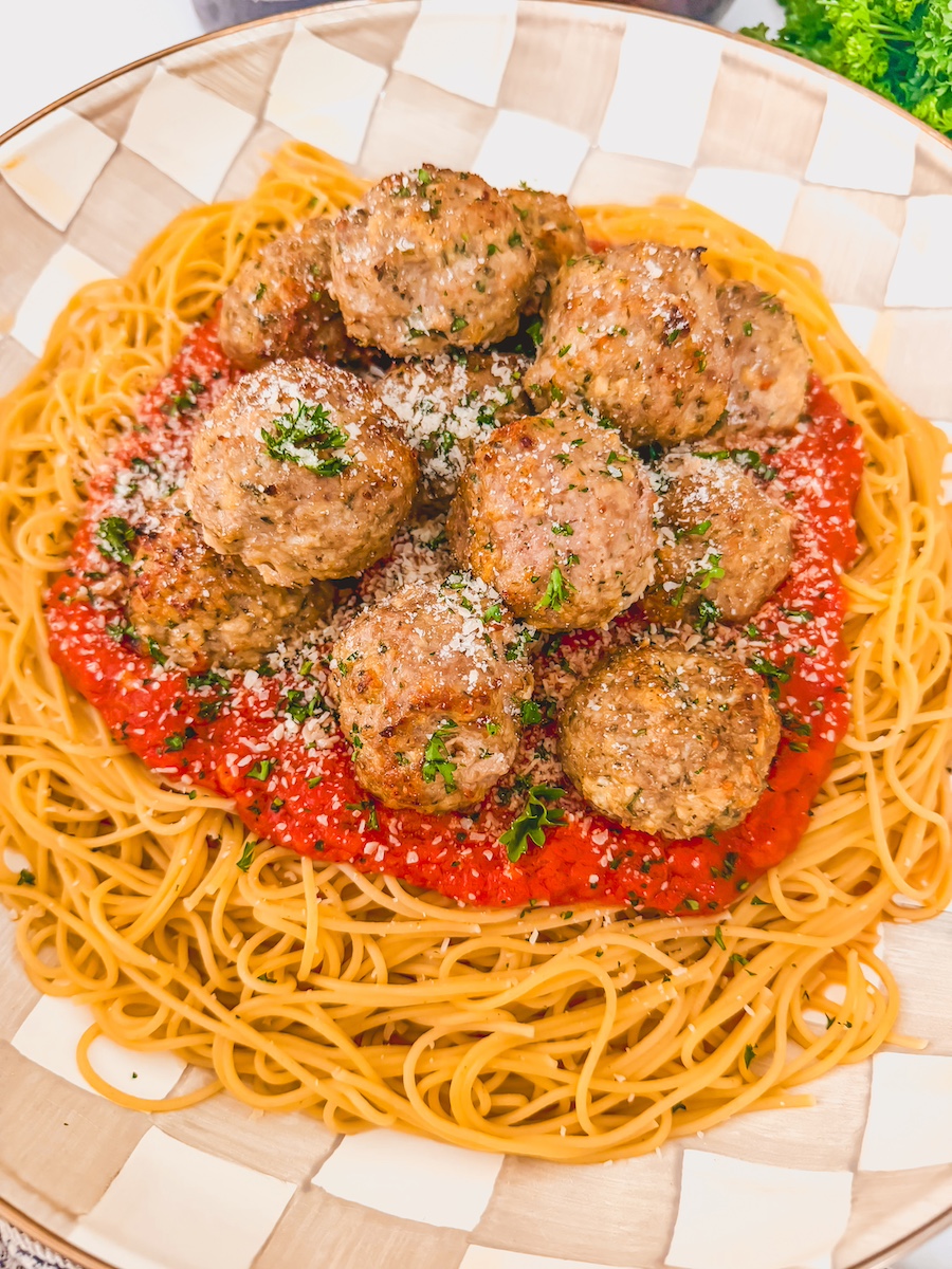 platter of pasta, sauce and meatballs garnished with cheese and herbs
