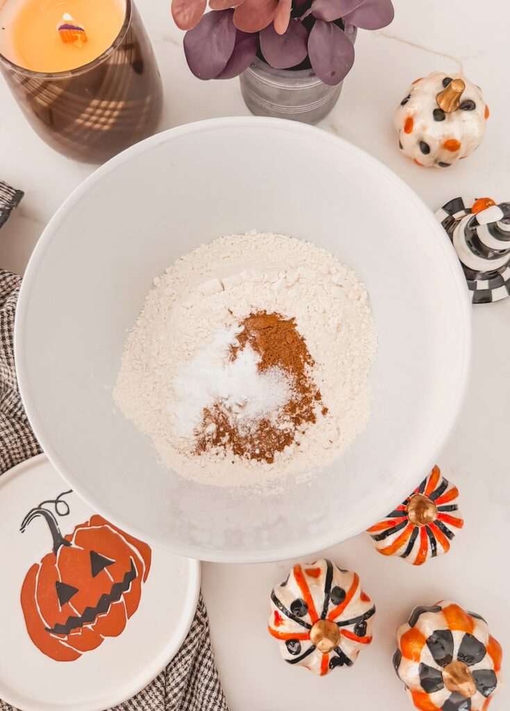 dry ingredients in white mixing bowl with halloween decor around bowl