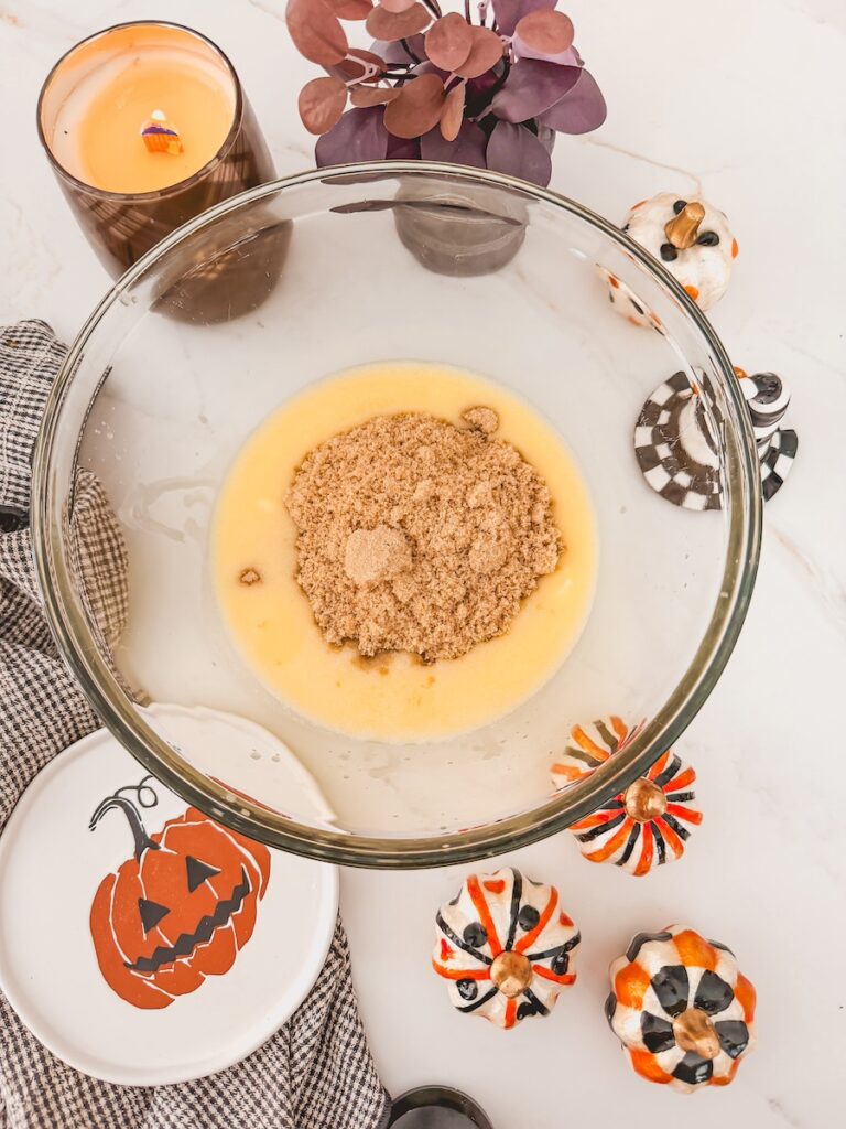 ingredients for pumpkin blondies starting to be added to glass bowl with halloween decorations around bowl