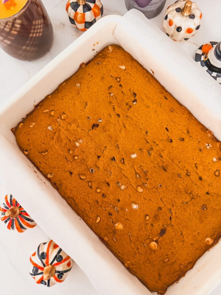 baked pumpkin blondies in baking sheet with mini decorative pumpkins around it