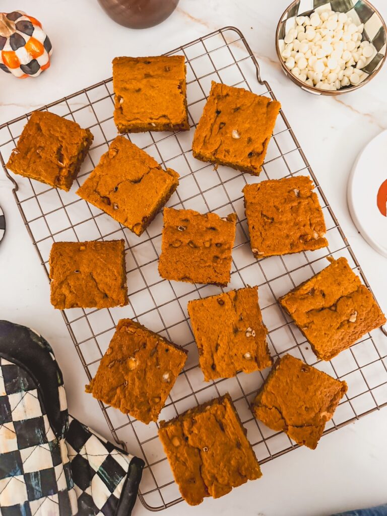 overhead shot of pumpkin blondies on a rack with white chocolate chips in a bowl next to rack