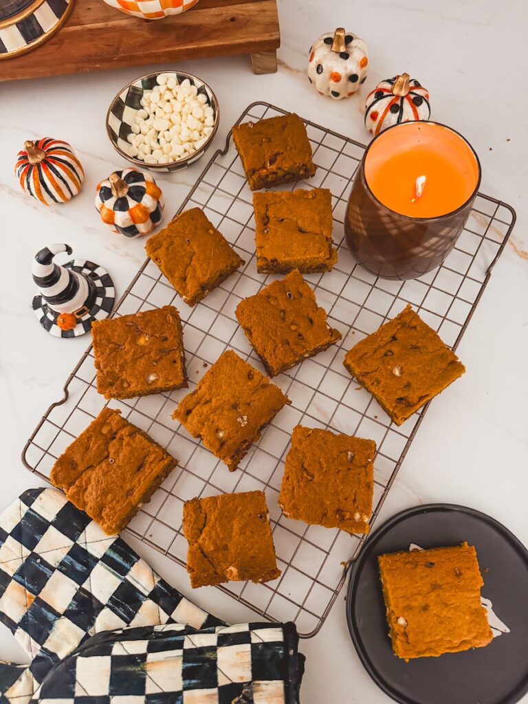 pumpkin blondies on a rack next to halloween decor and a candle