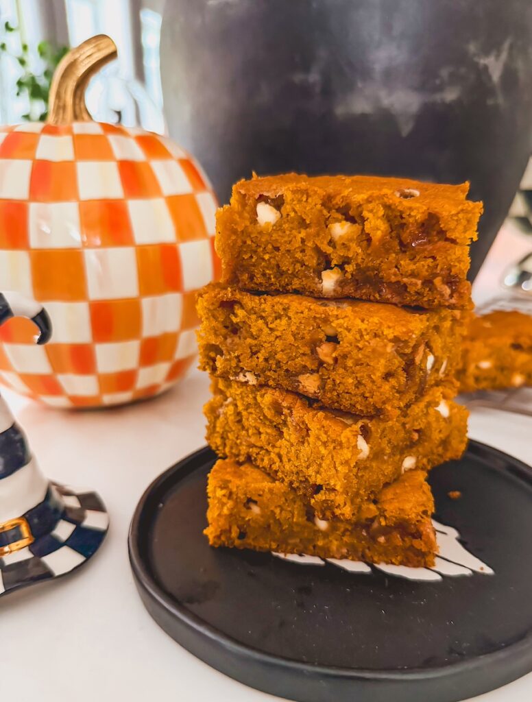 stack of 4 pumpkin blondies on black plate with checkered pumpkin in background