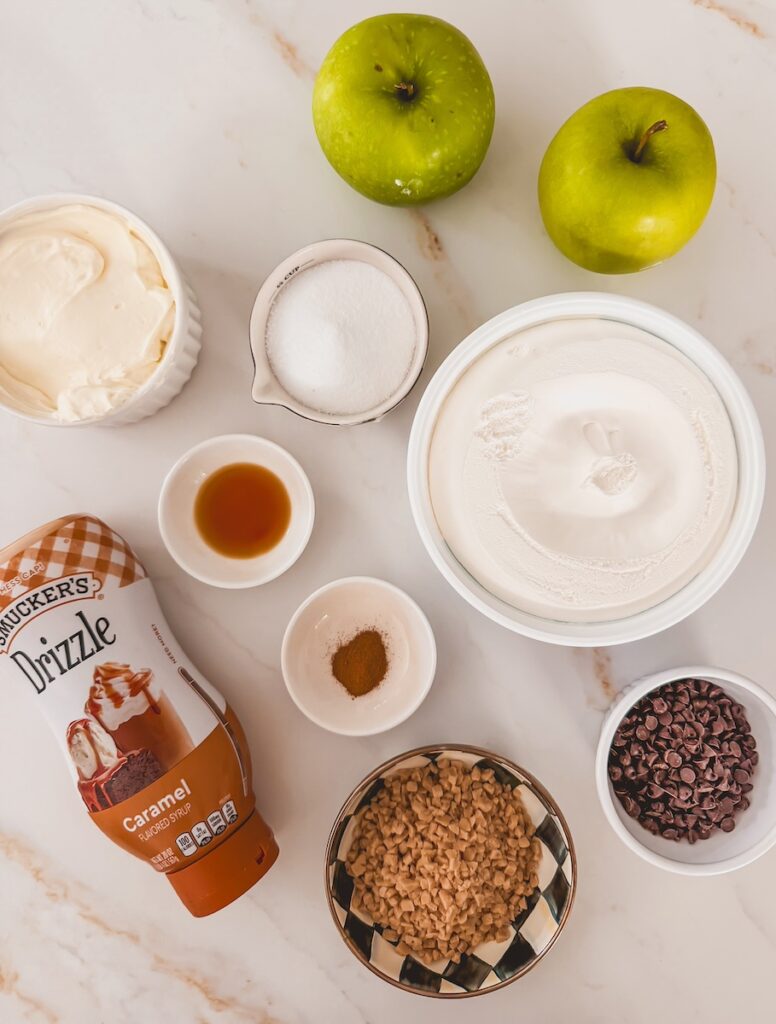 flatlay of ingredients including, whipped topping, cream cheese, vanilla, sugar, caramel sauce, heath bar pieces, mini chocolate chips