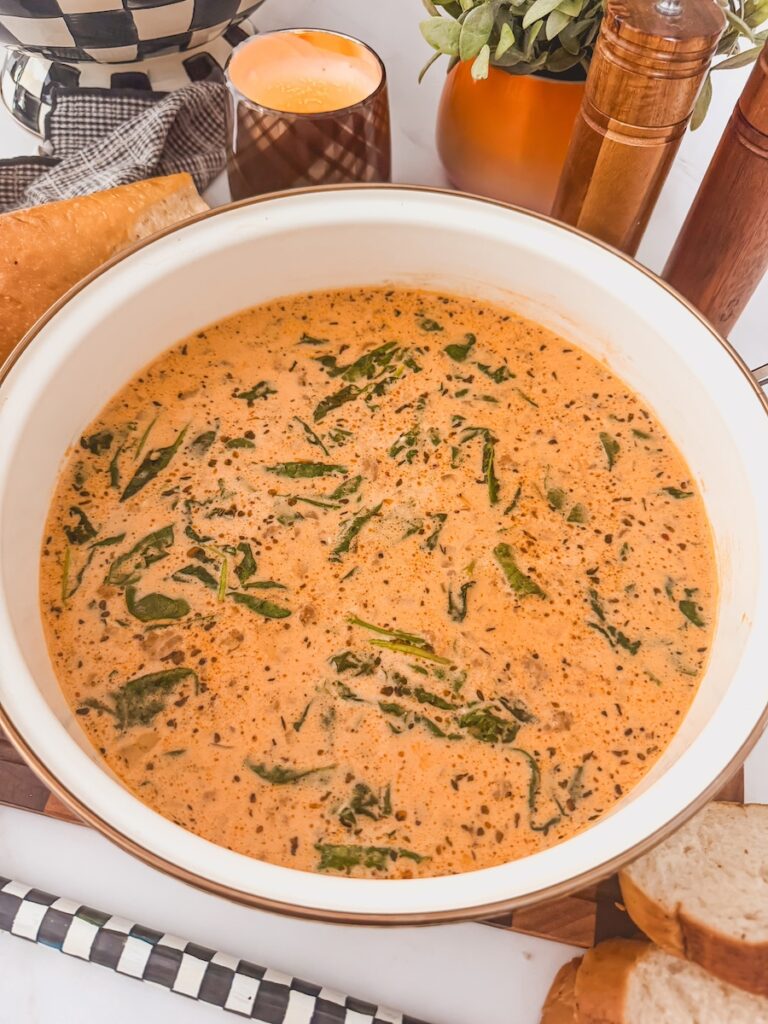 Italian sausage gnocchi soup ready to serve in a white pot.