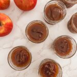pumpkin apple butter in glass jars next to whole apples