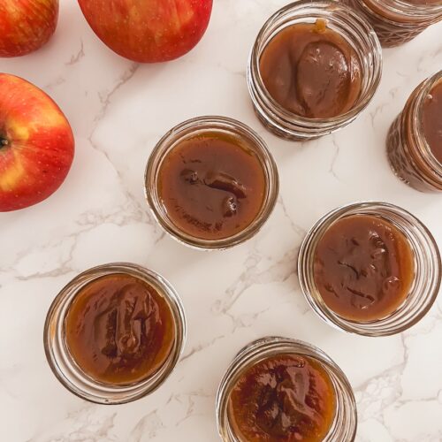 pumpkin apple butter in glass jars next to whole apples