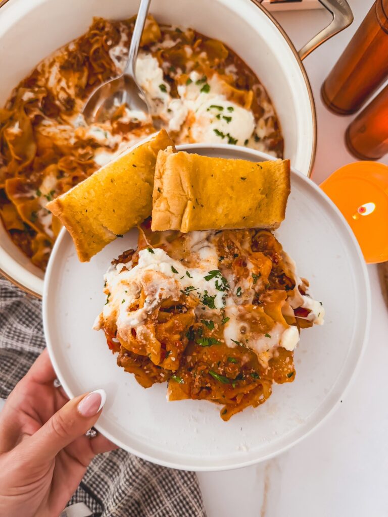 skillet lasagna on white plate with garlic bread