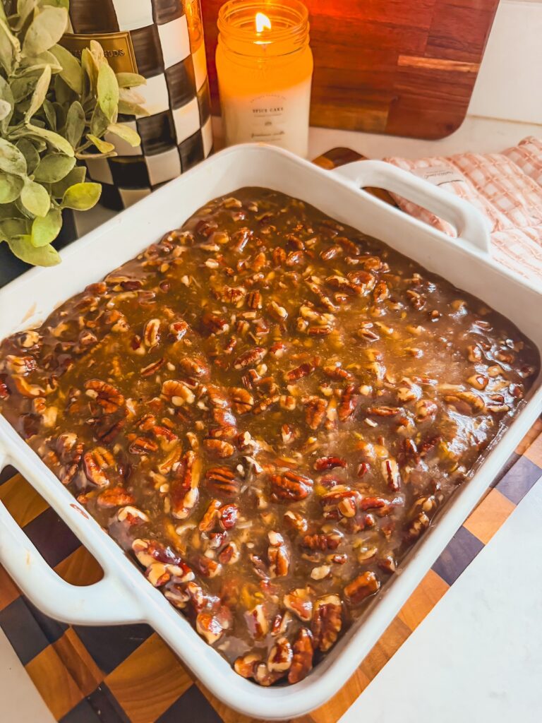 pecan pie filling on top of brownies in white baking dish