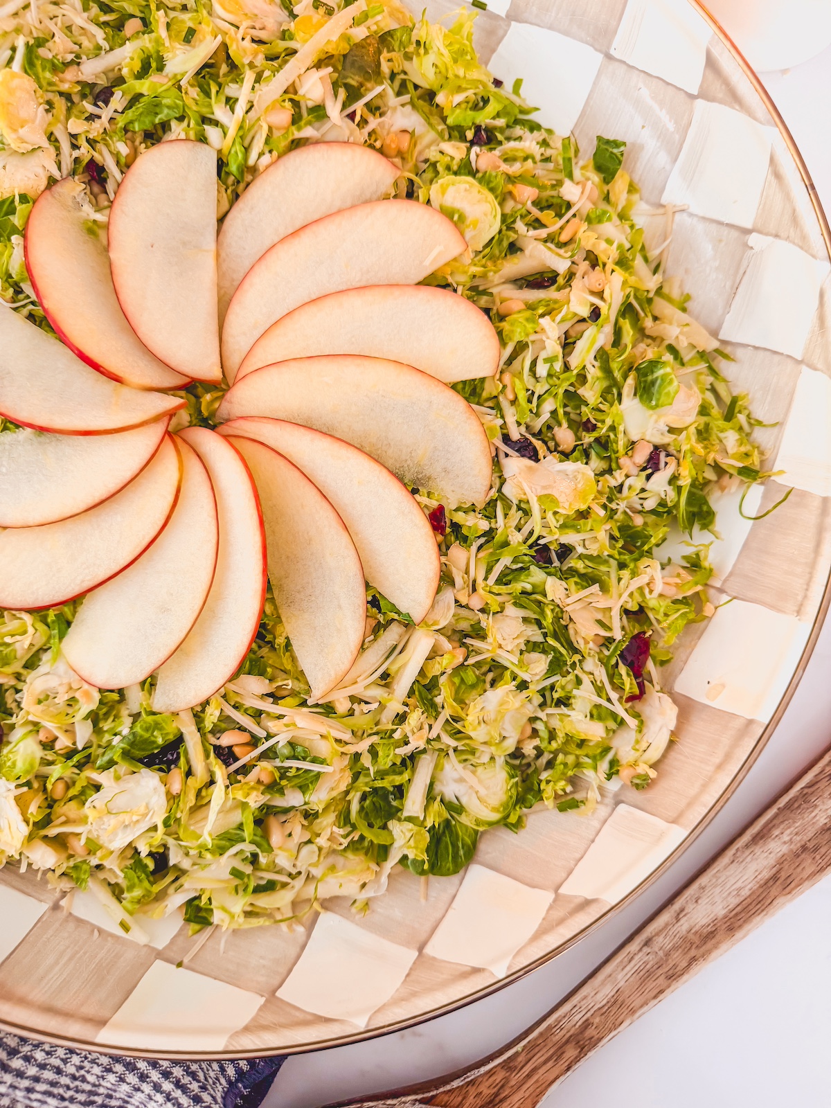 shaved brussels sprouts salad with fanned apple on top, on checked plate