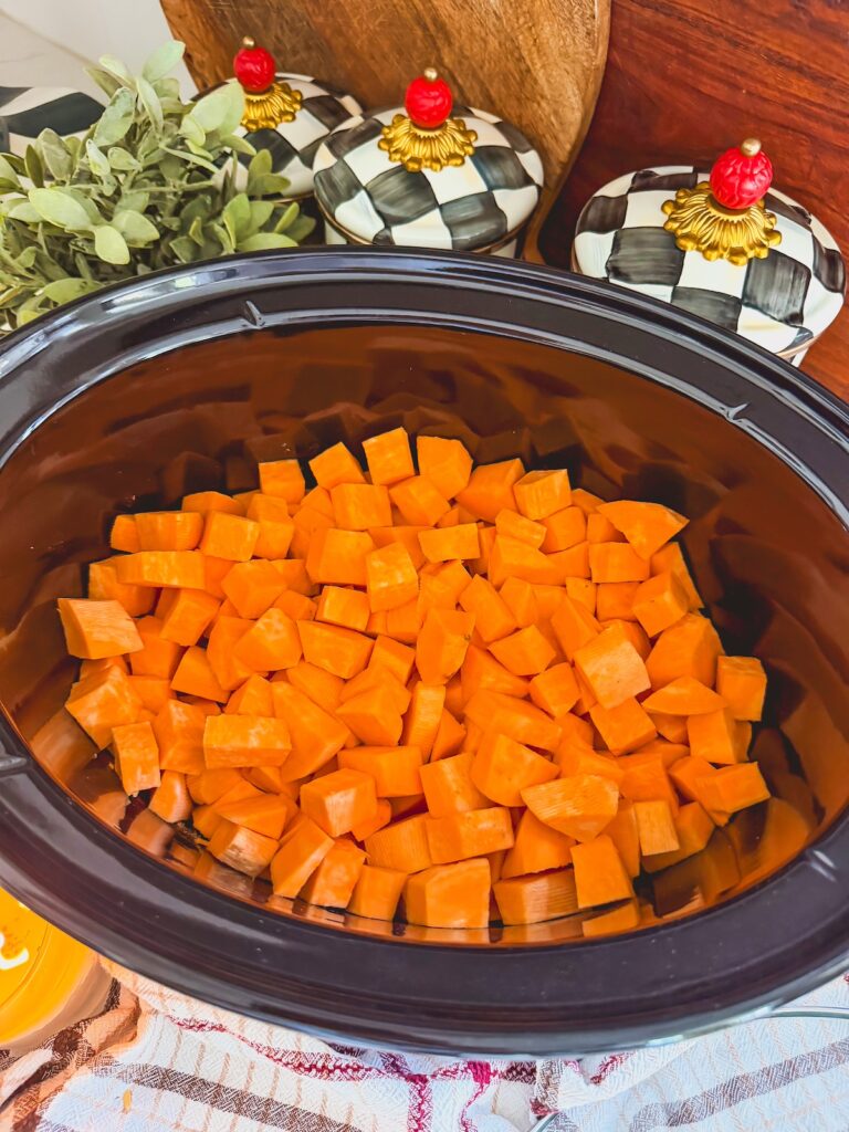 raw sweet potatoes in bottom of slow cooker
