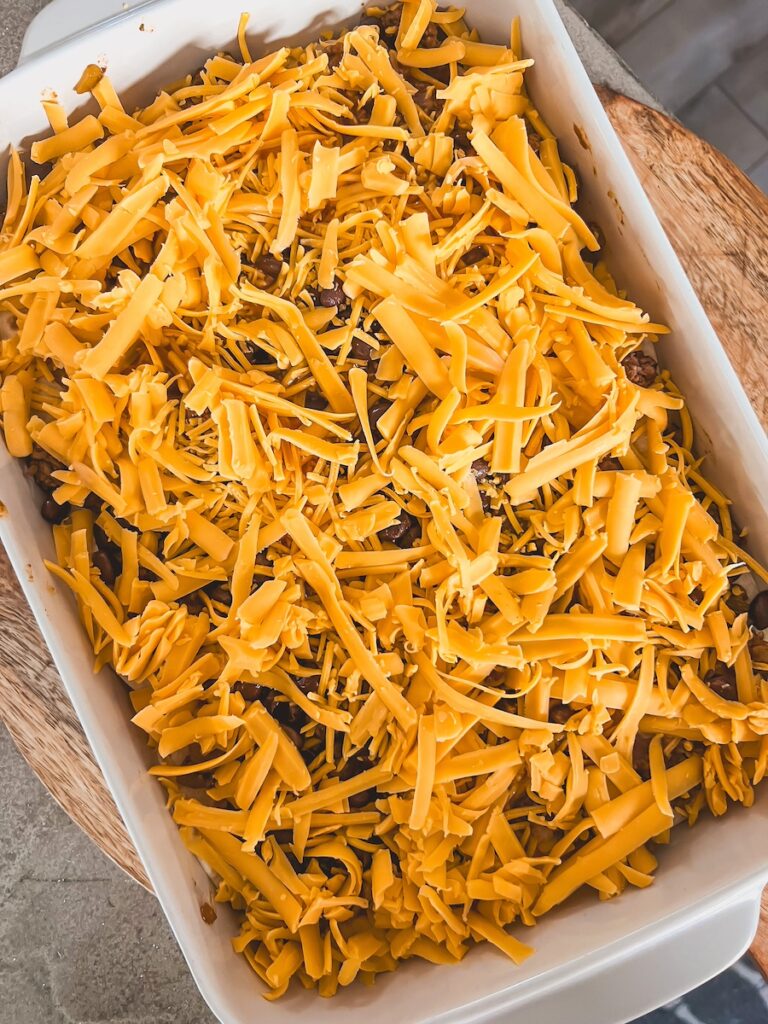 cheese layered on top of taco lasagna in baking dish