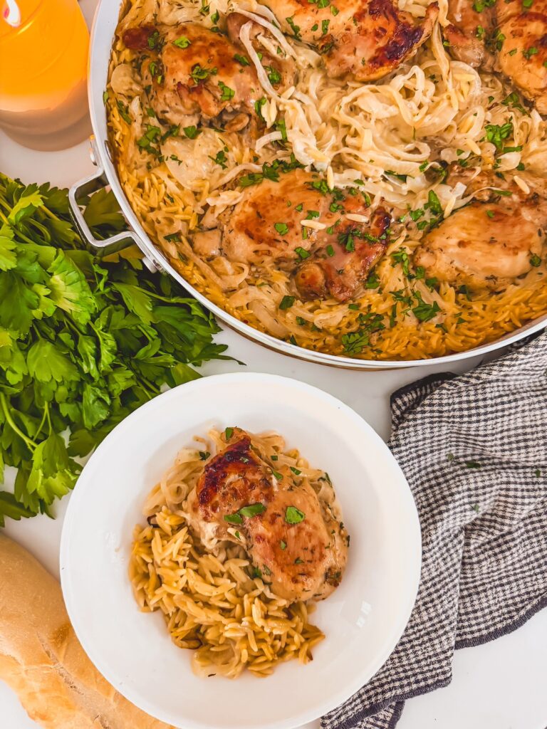 plate of french onion chicken and orzo next to skillet