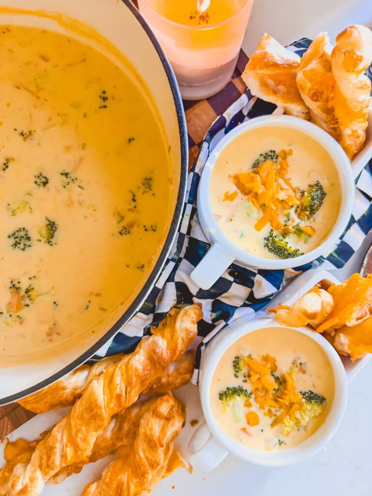 broccoli cheddar soup in dutch oven next to bowls of soup